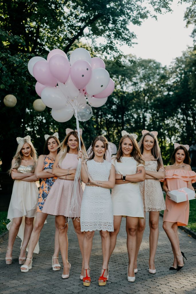 Women in dresses holding pink and white balloons, celebrating on the PST Trolley for bachelorette parties