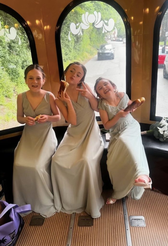 Three girls in dresses savoring donuts while riding the PST Trolley