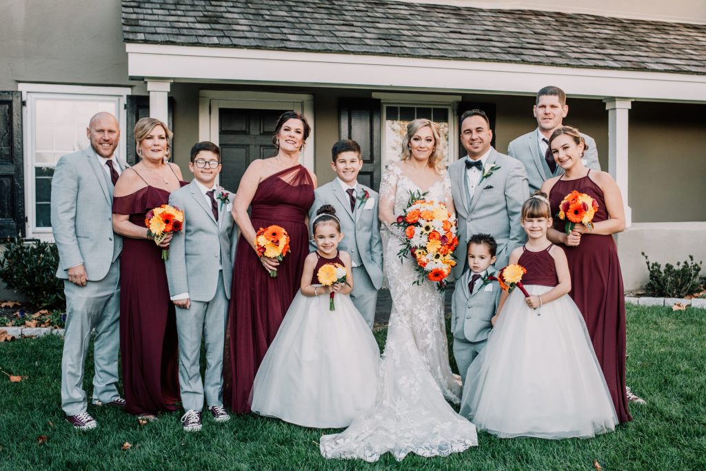 Bride, groom, and guests smiling outside for a wedding photo, PST Trolley in background