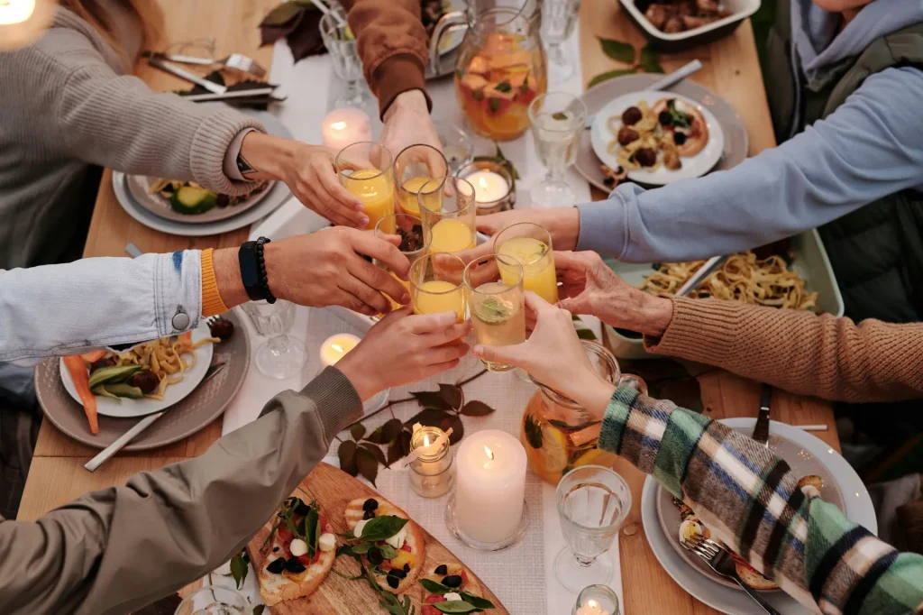 People celebrating with food and drinks at a dinner table.