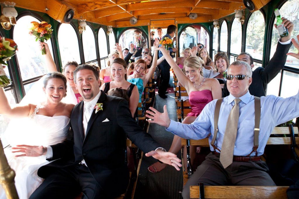 Happy group of people with raised arms enjoying a wedding party on a PST Trolley in Philadelphia
