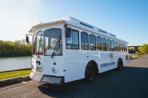 A white bus parked on the side of the road - PST Trolley