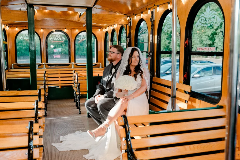 A bride and groom happily pose on the back of a PST Trolley, capturing a moment of their wedding celebration.
