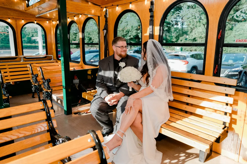 A bride and groom sit together on the back of a trolley, radiating joy on their wedding day.